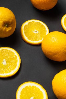 High angle view of whole and cut oranges on black background