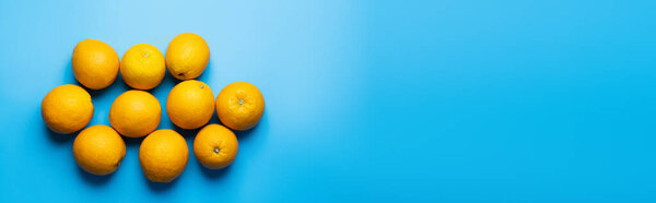 Top view of ripe oranges on blue background with copy space, banner 