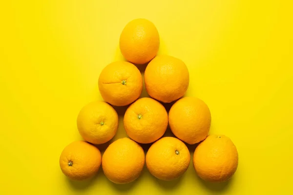 Colocación Plana Con Naranjas Forma Triángulo Sobre Fondo Amarillo — Foto de Stock