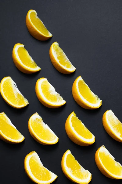Flat lay with pieces of oranges on black background
