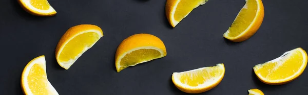 Top view of organic orange slices on black background, banner