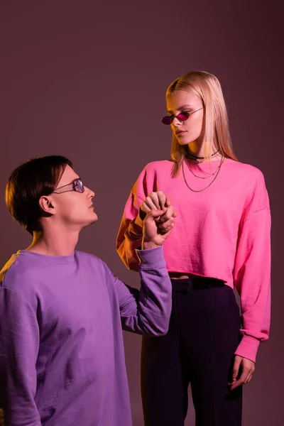 Young Couple Sweatshirts Sunglasses Holding Hands Isolated Purple Lighting — Stok fotoğraf