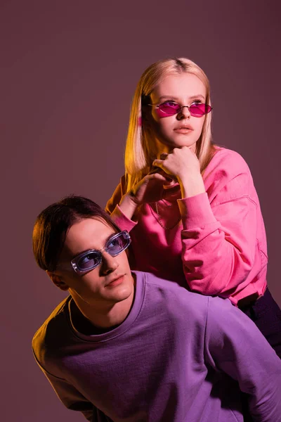Trendy Young Couple Sunglasses Looking Away Isolated Purple Lighting — 스톡 사진