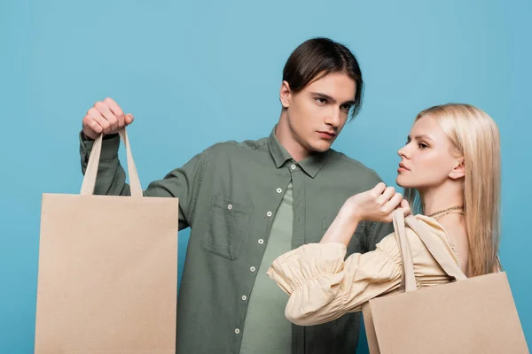 Pretty Young Woman Holding Shopping Bag Boyfriend Isolated Blue — Φωτογραφία Αρχείου