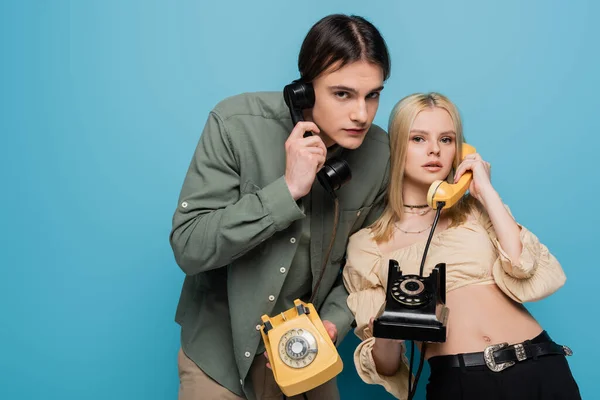 Stylish Couple Talking Retro Telephones Looking Camera Blue Background — Stock Photo, Image