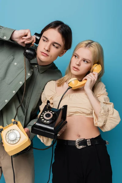 Fashionable Couple Talking Telephones Looking Away Blue Background — Stockfoto