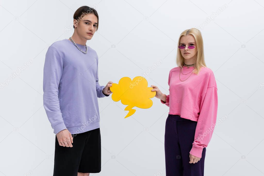 Stylish young couple holding thought bubble isolated on grey 