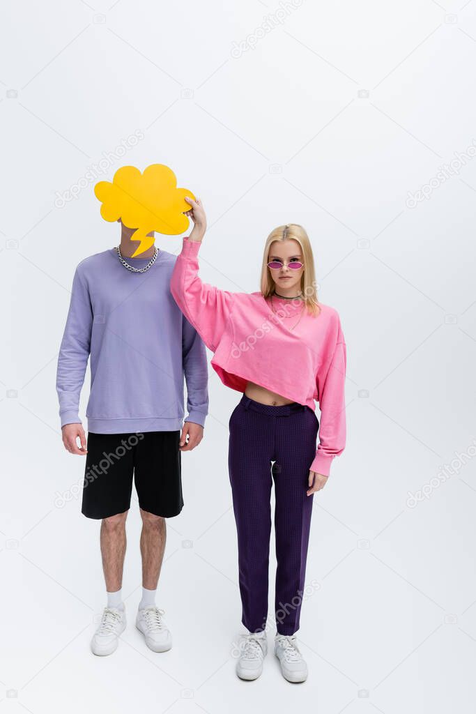 Stylish model in sunglasses holding thought bubble near boyfriend on grey background