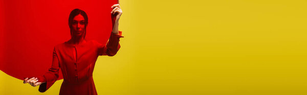 стильная молодая женщина в красном платье с круглой формы стекла изолированы на зеленый, баннер