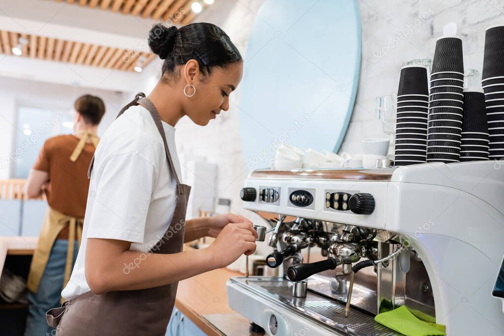 African american barista making coffee near machine in confectionery 