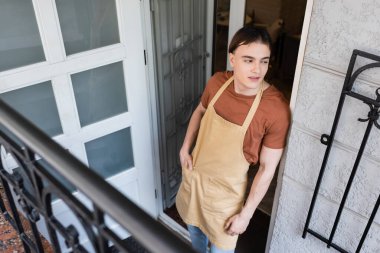 High angle view of young salesman standing near entrance of confectionery 