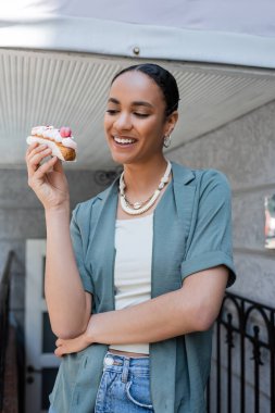 Tatlı dükkanının yanında kremalı pasta tutan Afrikalı Amerikalı bir müşteri. 