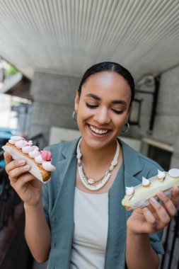 Pozitif Afro-Amerikan müşteri açık hava şekerleme dükkanının yanında eklerleri tutuyor. 