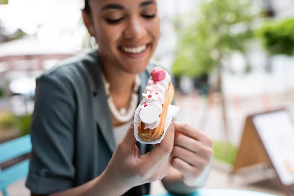 Cheerful African American Woman Holding Eclair Cream Outdoors — Stockfoto