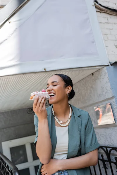 Pleased African American Woman Holding Delicious Eclair Sweet Shop — Fotografia de Stock