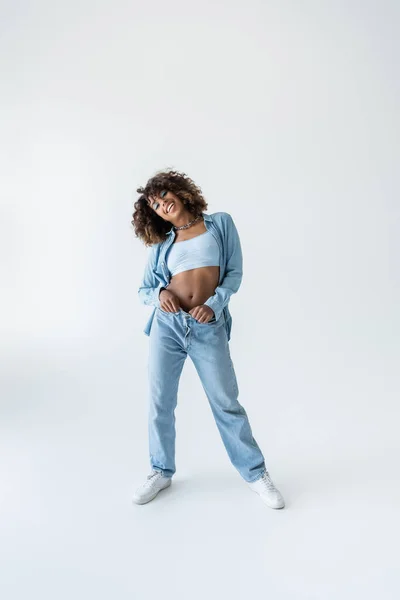 Mavi Kot Pantolon Gri Arka Planda Spor Ayakkabı Giyen Afro — Stok fotoğraf