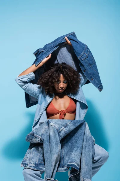 Trendy African American Woman Holding Denim Jacket Vest While Sitting — 스톡 사진