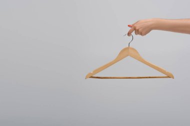 partial view of model holding wooden hanger isolated on gray