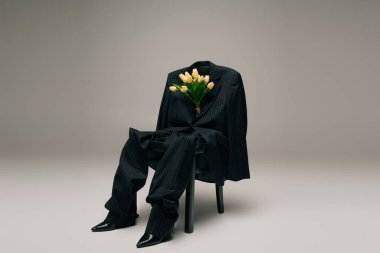 blooming fresh tulips and blue stylish suit hanging on chair on grey background