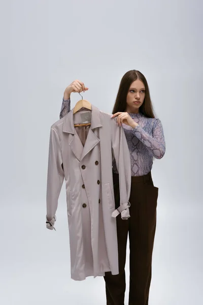 Teenage Model Holding Recyclable Trench Coat Hanger Isolated Grey — Photo