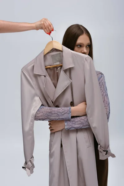 Teenage Model Hugging Stylish Trench Coat While Woman Holding Hanger — Foto de Stock