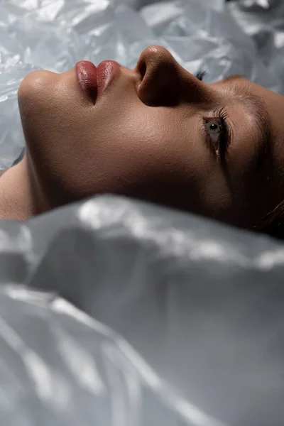 close up of teenage model lying around plastic bags, recycle fashion concept