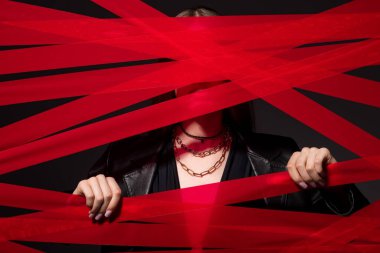 cropped model touching red strips from adhesive tape isolated on black, recycle fashion concept