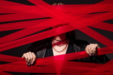 cropped model touching red strips from adhesive tape isolated on black, recycle fashion concept