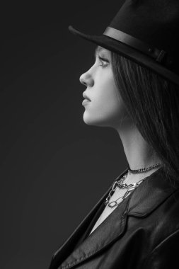 profile of teenage model in fedora hat posing in studio, monochrome photo