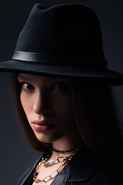 portrait of teenage model in fedora hat looking at camera isolated on grey