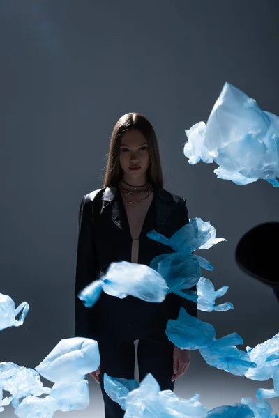 Brunette Model Black Suit Posing Flying Blue Plastic Bags Dark — Stock Photo, Image