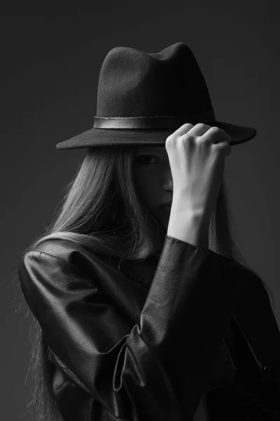 monochrome photo of model adjusting fedora hat in studio