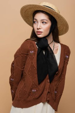 Stylish woman in vintage clothes and sun hat looking away isolated on beige 