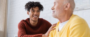 Positive african american man hugging blurred grandparent at hoe, banner 