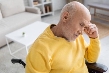 Disappointed senior man sitting in wheelchair at home 