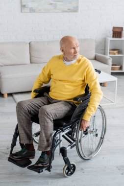 Elderly man looking away while sitting in wheelchair at home