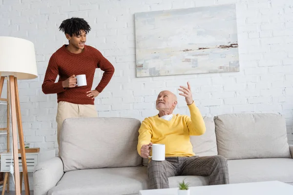 Smiling Granddad Holding Cup Talking African American Grandson Living Room — Foto de Stock