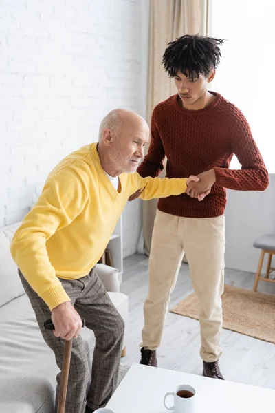 African American Grandson Helping Senior Granddad Walking Came Tea Home — Zdjęcie stockowe