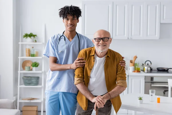 Cheerful African American Nurse Hugging Elderly Patient Walking Cane Home — 图库照片