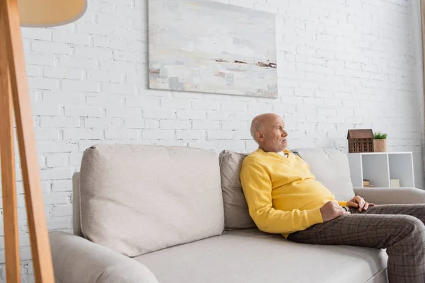 Displeased Senior Man Looking Away While Sitting Couch Home — Stockfoto