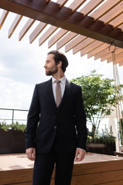 Side view of brunette groom looking away on terrace outdoors 
