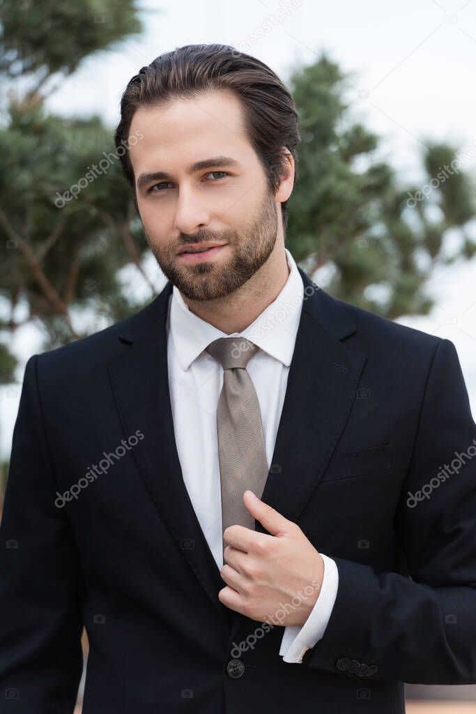 Portrait of young bearded groom looking at camera outdoors 