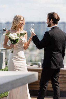 Cheerful newlyweds clinking with champagne on terrace of restaurant 