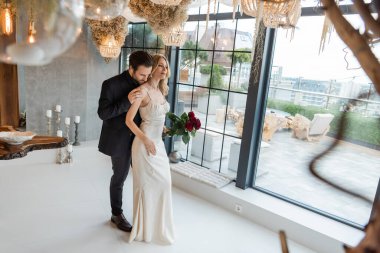 Man in suit touching elegant girlfriend in dress with roses in restaurant 