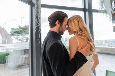 Side view of elegant man hugging blonde girlfriend in restaurant 