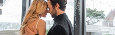 Side view of bearded man hugging blonde girlfriend in restaurant, banner 