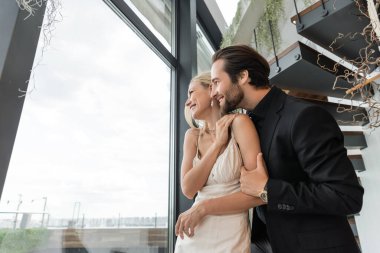 Side view of cheerful romantic couple looking at window in restaurant 