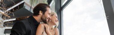 Side view of smiling romantic couple looking at window in restaurant, banner 