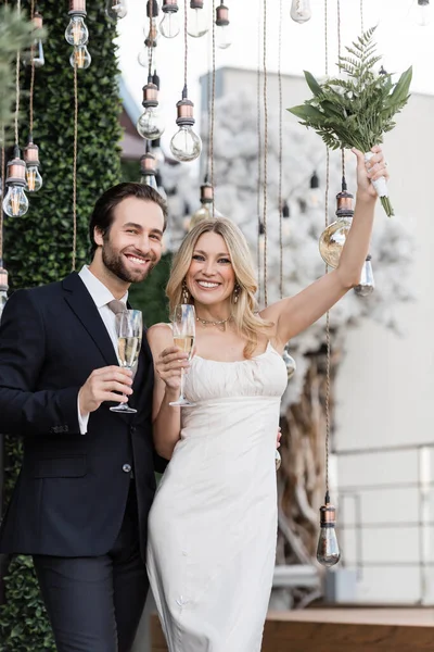 Happy Bride Holding Bouquet Champagne Groom Light Bulbs Terrace — Stok fotoğraf