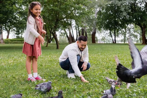 Positive Asian Family Feeding Doves Lawn Summer Park — Foto de Stock